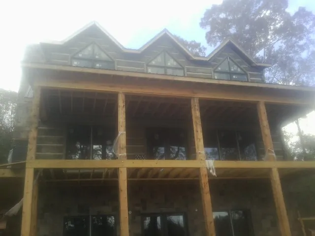 Dormers and porch framing on a large log home under construction — Roof Coating work by our crew in Wyoming